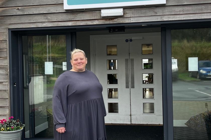 Woman stands outside of care home smiling