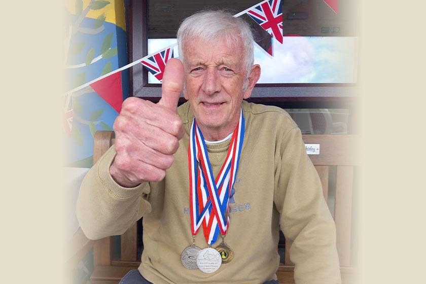 Keith, a care home resident at Trevarna in Cornwall, proudly displays his medals following the care home's own version of the summer games