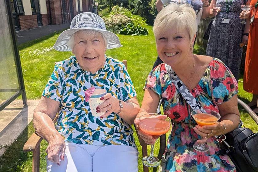 Vivienne and Janet sat in a grassed garden area at Barony Lodge with summer drinks