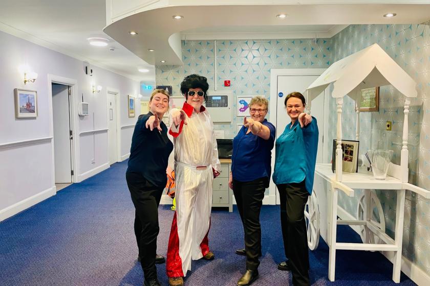 Three female members of staff at Sanctuary care posing with an Elvis impersonator