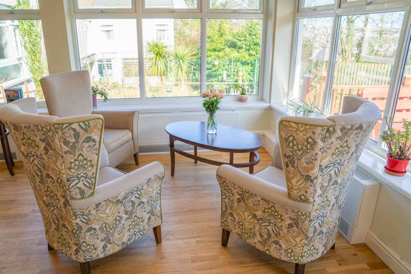 Three high backed arm chairs arranged around a wooden coffee table