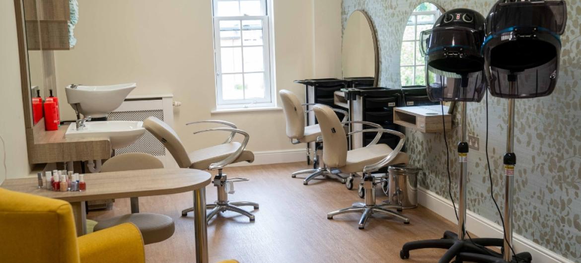 A salon with stylish chairs, a hair dryer, and a mirror for customers to enjoy hair styling services.