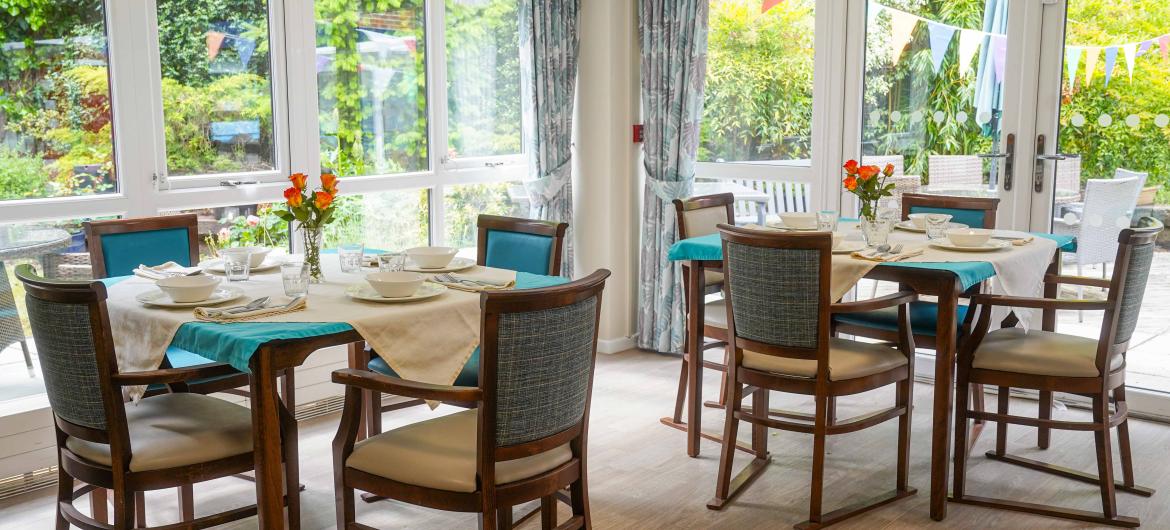 A dining area with table and chairs in a conservatory looking out into the garden area