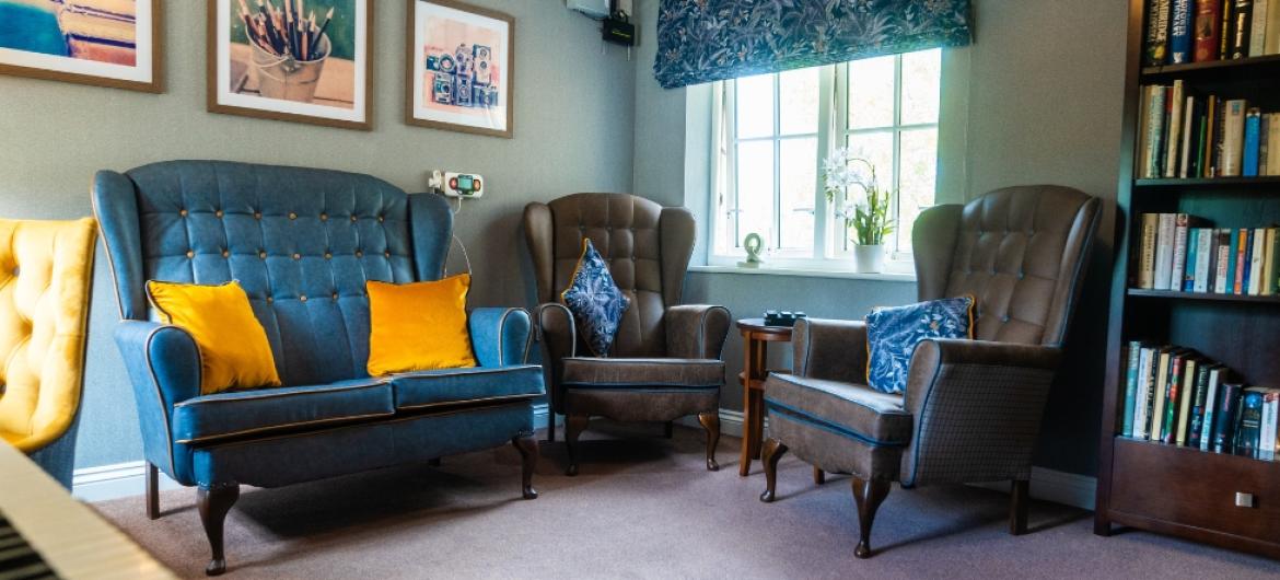 A cosy room with bookshelves, two brown leather armchairs and a blue sofa 