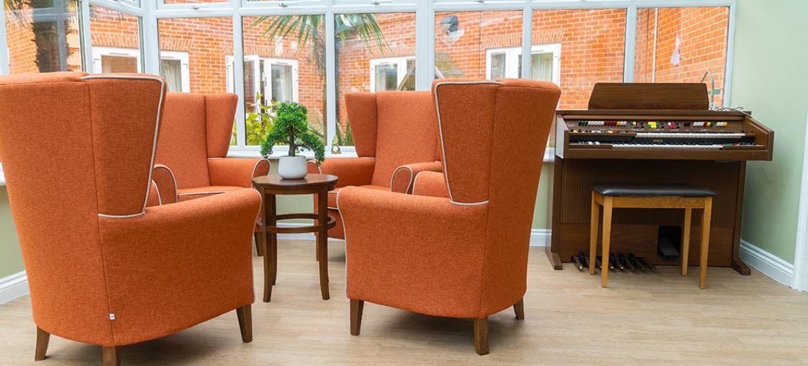 Beautiful conservatory with armchairs and a piano at Wantage Care Home in Oxfordshire