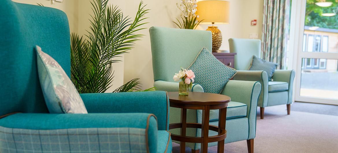 A line of turquoise armchairs separated by side tables in front of a cream wall