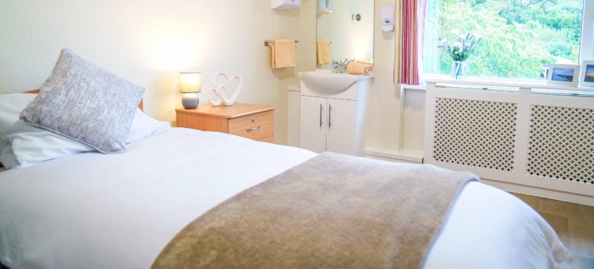 A neutrally decorated, spacious bedroom with a single bed at Blackwood Care Home