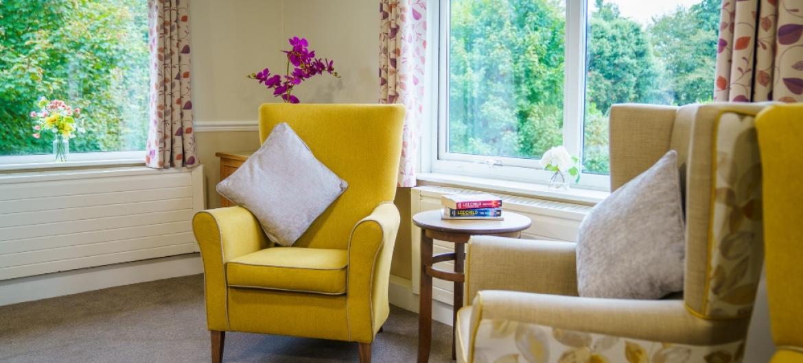 Two comfortable arm chairs in a well lit room next to large windows with a view to the garden