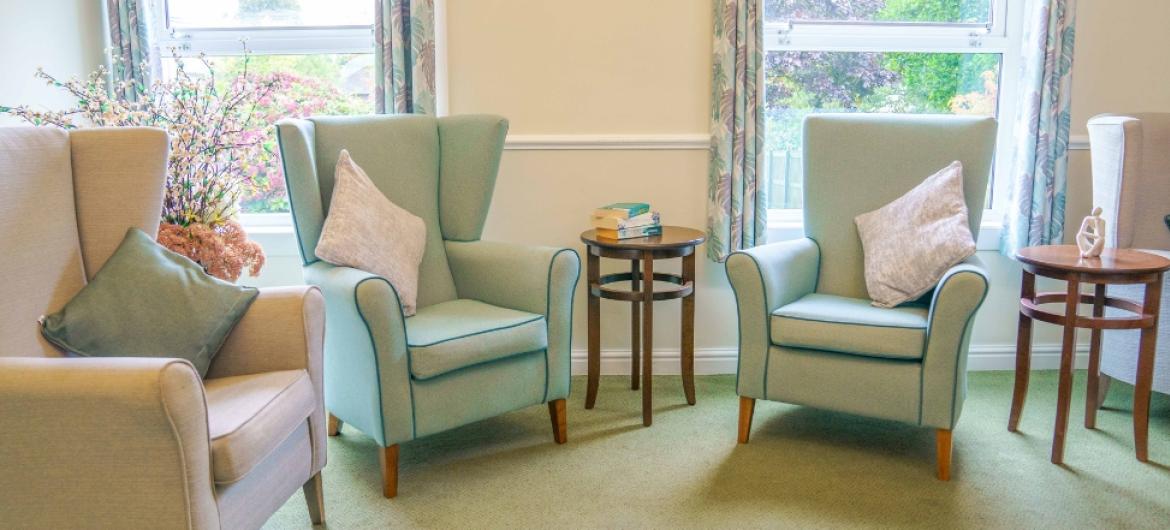 A group of comfortable armchairs in a brightly lit room next to the windows