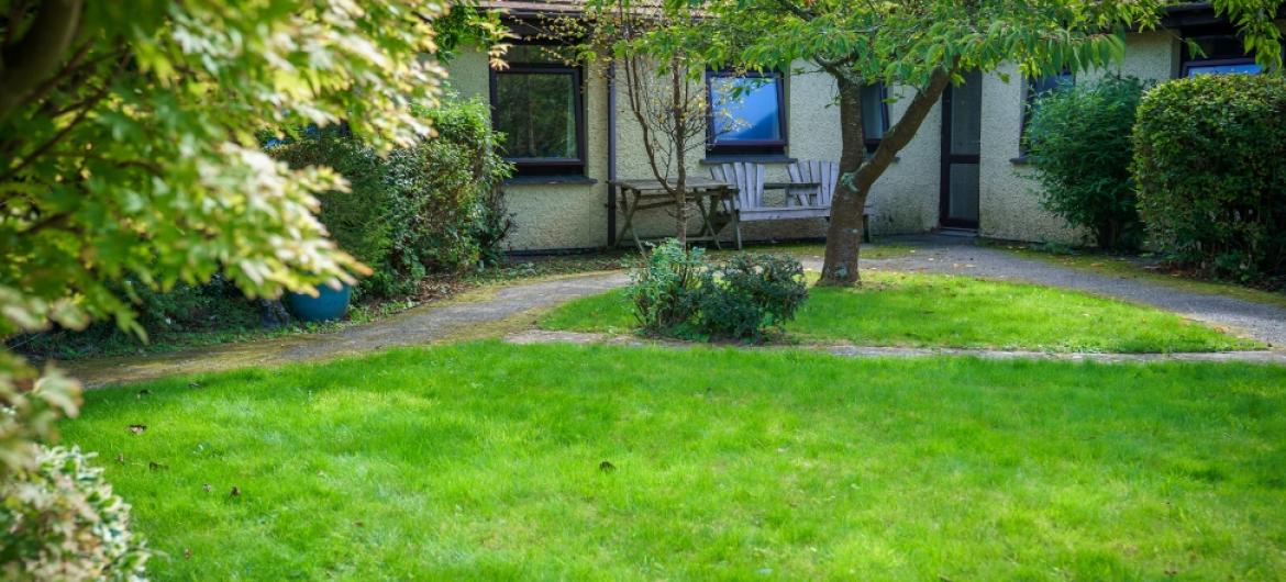 The exterior of Trevarna, luscious green grass with outdoor seating