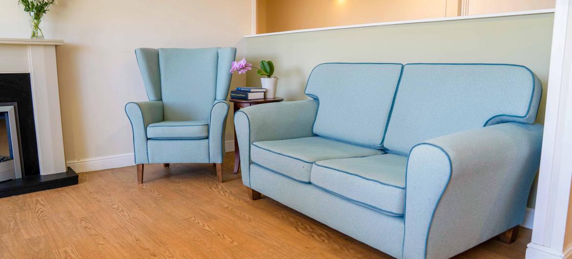 A blue two-seater sofa and matching armchair on a hardwood floor