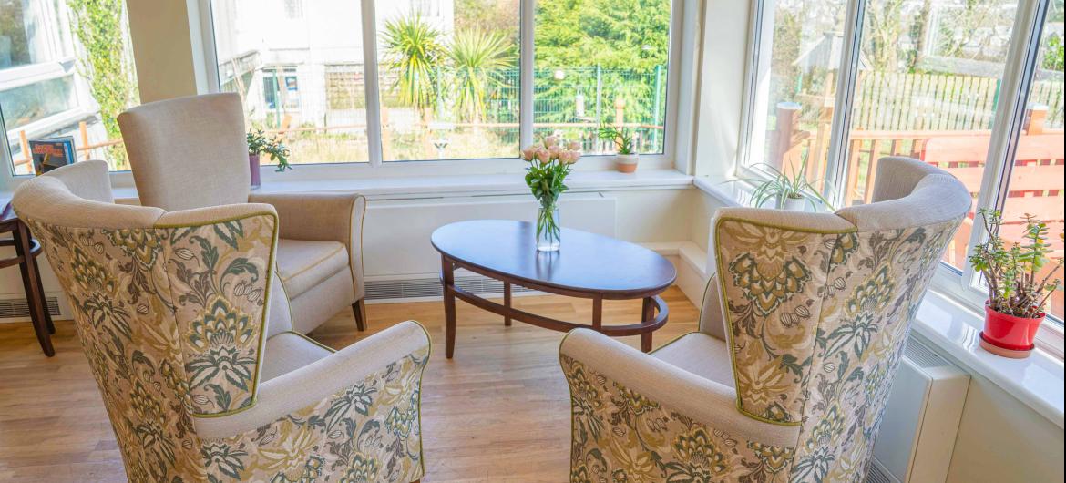 Three high backed arm chairs arranged around a wooden coffee table