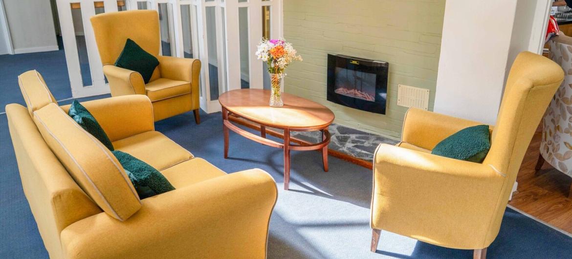 The green, living space A vibrant yellow sofa with two matching arm chairs located around a wall mounted electric fire.