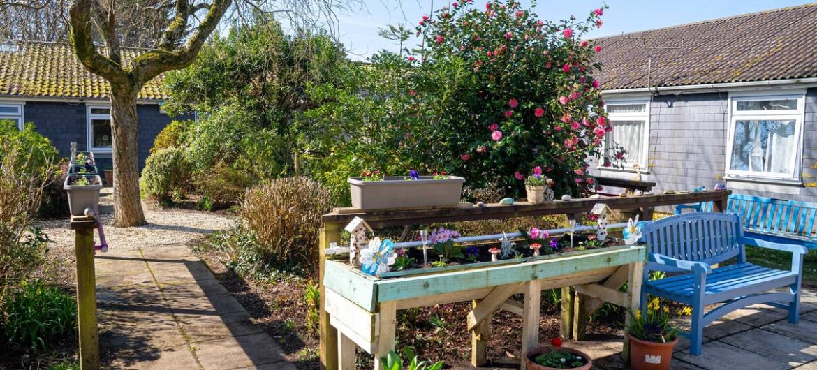 The Woodland, planting station A beautiful garden with comfortable blue benches. The paved paths are easy to navigate, creating a peaceful, accessible space where residents can relax and enjoy the outdoors.