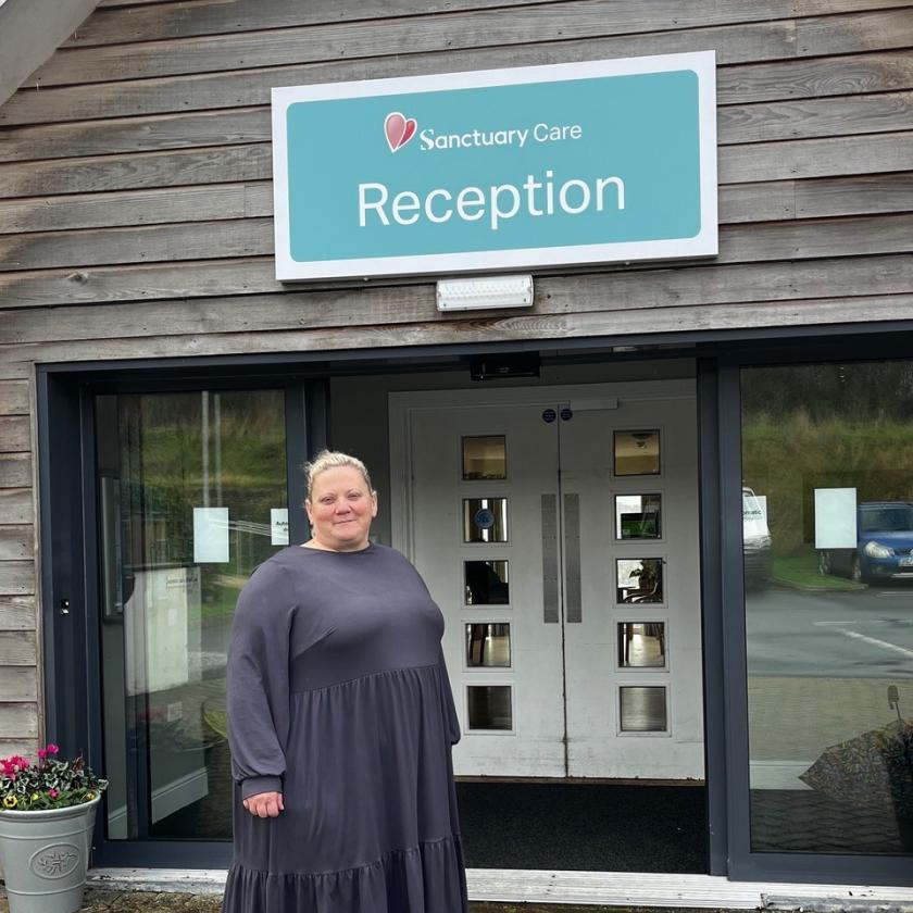 Woman stands outside of care home smiling