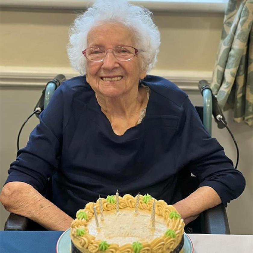 Ravenhurst resident Dolly sitting at a table with a birthday cake on the table