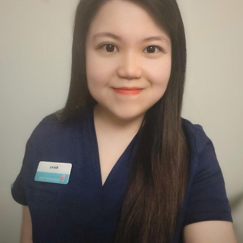 A woman wearing a Sanctuary Care name badge smiling at the camera