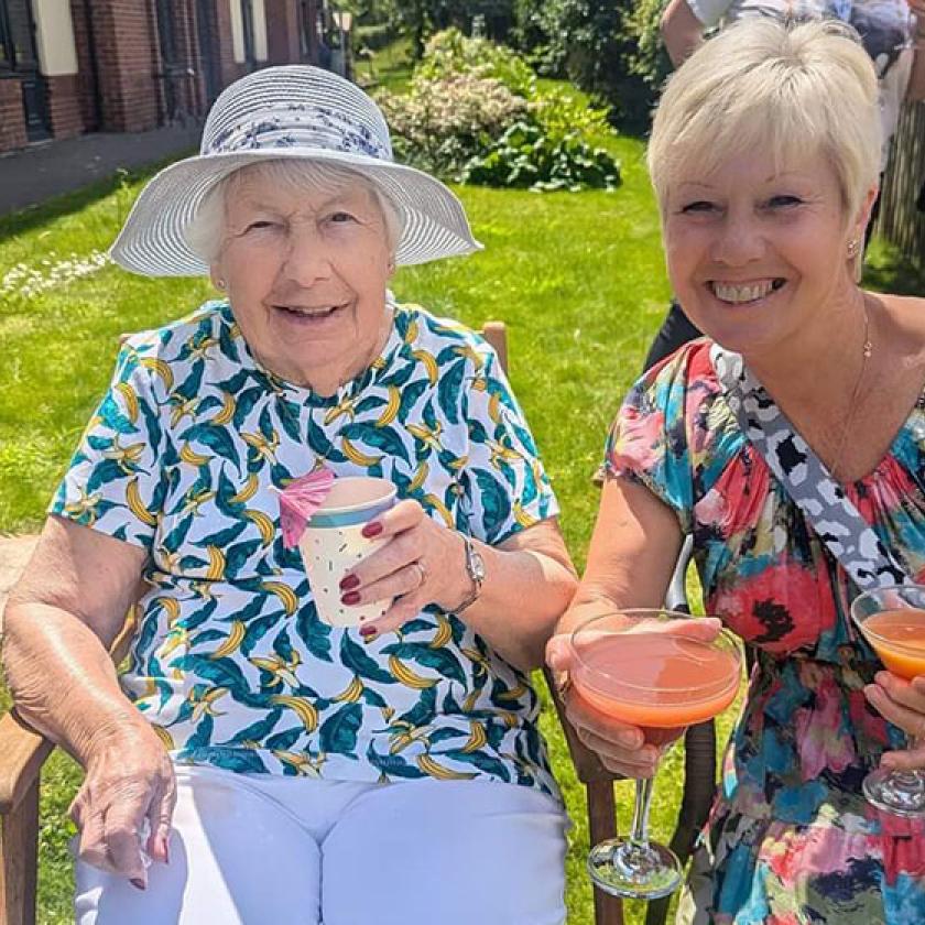 Vivienne and Janet sat in a grassed garden area at Barony Lodge with summer drinks