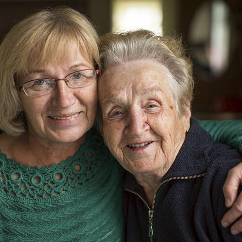 An elderly mother and her daughter embracing each other.