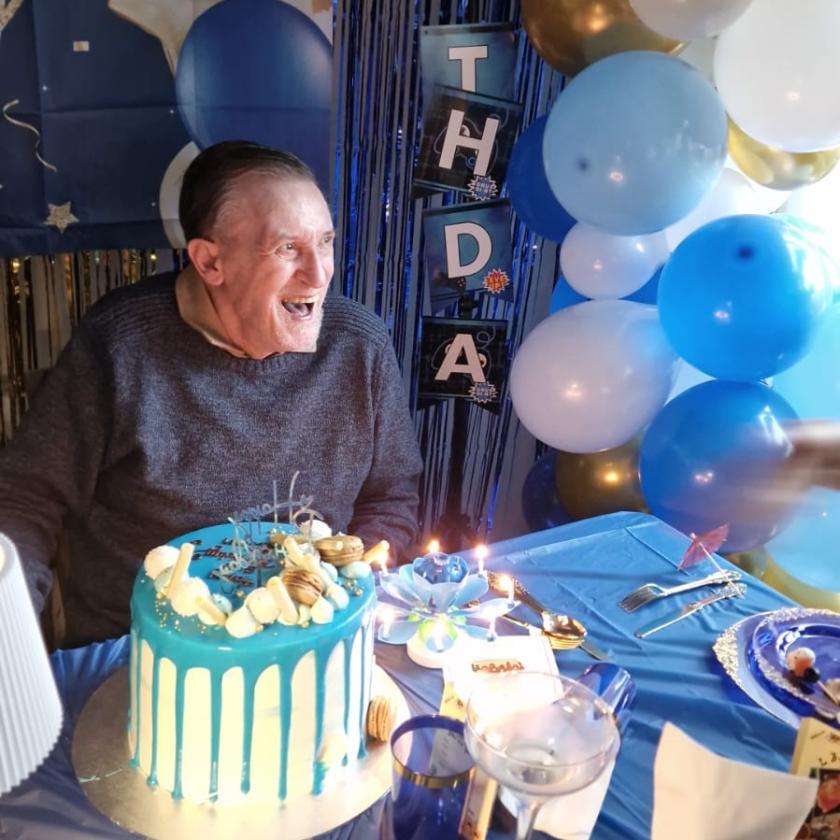 Resident Ian celebrating his birthday with a cake and balloons