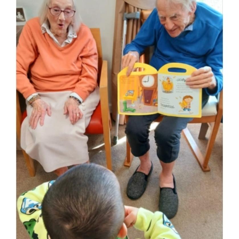 Two residents of Regent smiling and interacting with a child from a nearby nursery