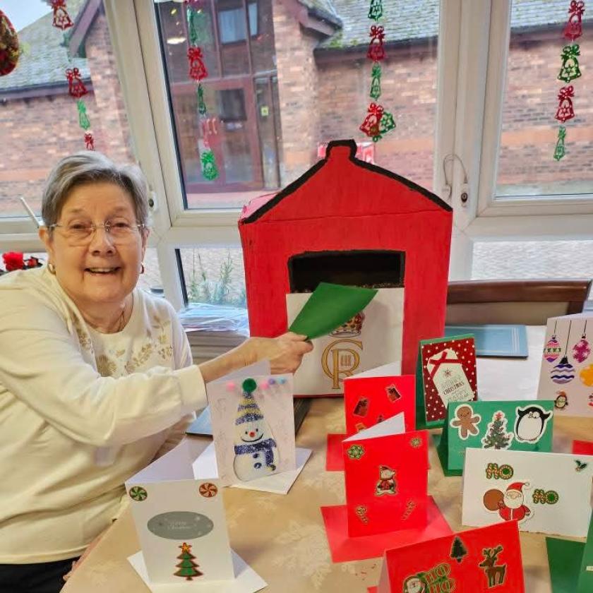 A resident posting a Christmas card into a homemade postbox